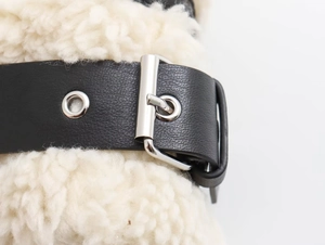Detail of beige fleece jacket with black leather strap and metallic buckle fastener