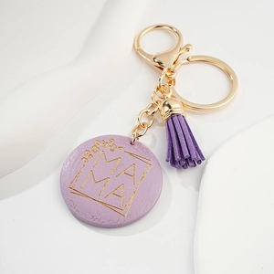 Detail of purple MAMA keychain with gold floral engraving and suede tassel charm