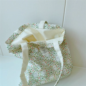 Detailed close-up of cream canvas tote bag with red floral and puppy prints with inner tag
