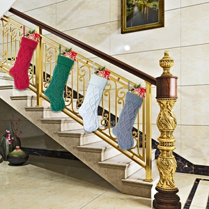 Set of four cable knit Christmas stockings in red, green, white, and grey hung on stairs