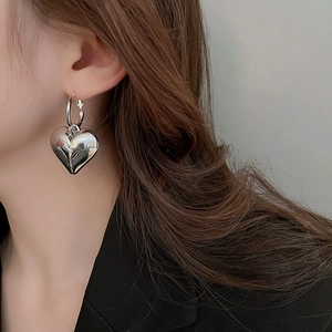 Close-up of polished silver heart dangle earrings worn with a black suit jacket