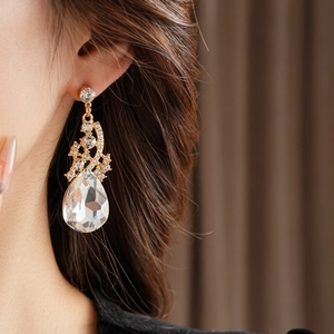 Gros plan d'une boucle d'oreille goutte d'or avec cristaux clairs sur l'oreille