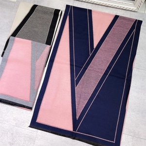 Detailed flat lay of long scarves with geometric V-pattern in pink, navy, and purple
