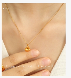 Close-up of a delicate gold water drop pendant necklace worn on a woman's collarbone