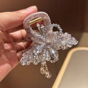 Close-up of floral hair claw clip featuring pink crystal center and long tassels