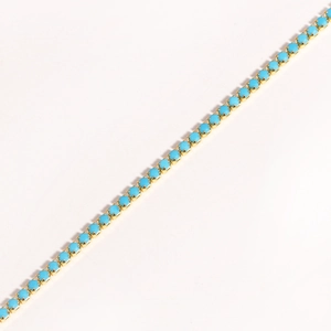 Detail of gold chain necklace featuring round sky blue cubic zirconia in prong setting