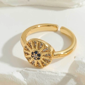 Macro detail of golden evil eye ring with blue and white zircon stones on stone background