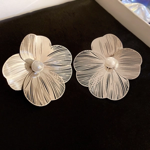Macro view of floral stud earrings with hollow petal design and a central pearl detail