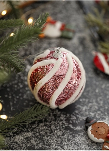 Rosafarbene Weihnachtskugel mit Glitzer und weißen Plüschwirbeln in festlicher Deko