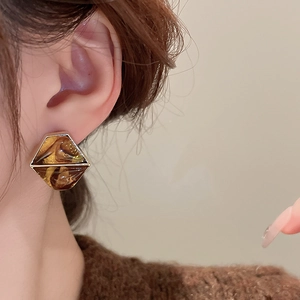 Close-up of amber resin hexagonal earring with gold plating on a model's ear