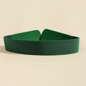 Detail of green elastic wide waist belt with leather texture clasp on beige background