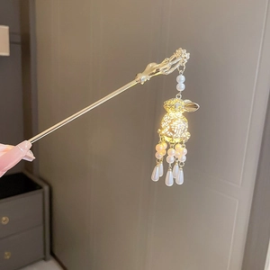Vue détaillée de l'épingle à cheveux dorée avec lanterne lapin lumineuse et pompon
