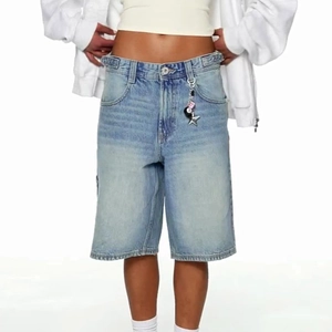 Detail der hellblauen Jeansshorts mit Sternanhängern und Metallknopfverschluss