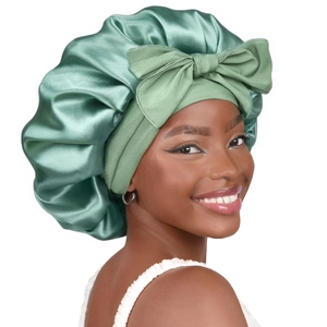 Sage green silk satin sleep bonnet featuring a large decorative bow and wide band