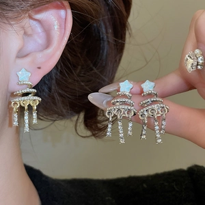 Macro shot of sparkling silver Christmas tree tassel earrings with crystal star detail