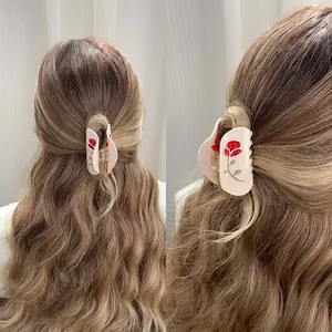 Elegant cream shark hair claw clip with red rose patterns on blonde wavy hair back view