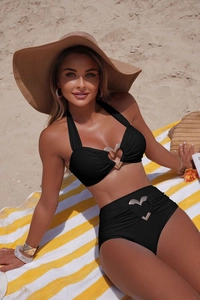 Dettaglio di bikini nero con fibbie a cuore argentate su un telo da spiaggia