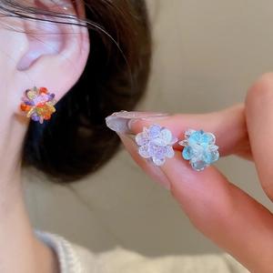 Close-up of crystal flower stud earrings in rainbow, purple, and blue floral designs