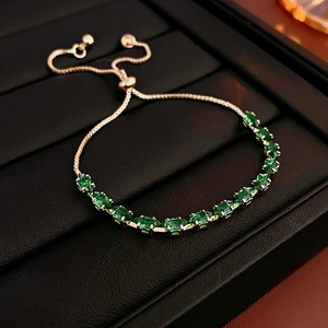 Detailed view of adjustable gold bracelet featuring elegant green oval-cut gemstones