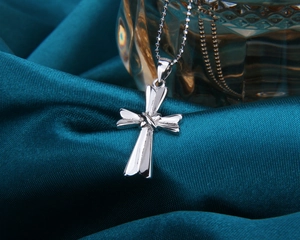 Détail d'un pendentif croix en argent sterling S925 sur un fond en soie bleu foncé
