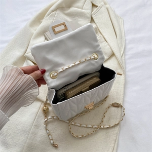 White quilted leather crossbody bag with gold chain strap on a blazer showing capacity