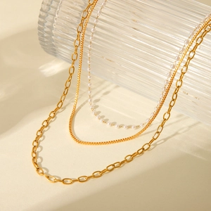 Three-layer 18K gold plated stainless steel necklace with elegant pearls on a glass bottle