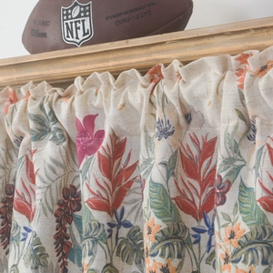 Floral linen cafe curtain with red and blue flower patterns hanging on a wooden rod
