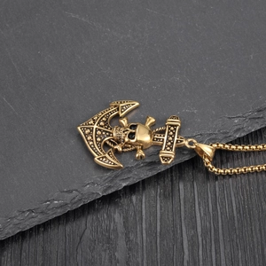 Detailed close-up of a vintage golden anchor and skull pendant on a rustic stone background