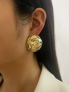 Macro detail of gold-plated semi-circle earrings with textured wavy surface on model