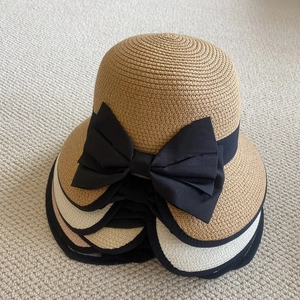 Detalle de sombreros de paja apilados con lazos negros y textura de tejido fino en colores
