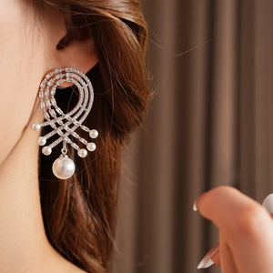 Gros plan de boucles d'oreilles argentées avec maille tressée, zircons et perles