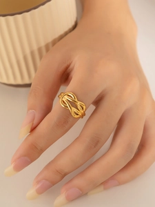 Close-up of 18k gold plated titanium ring featuring a hollow double knot design on finger