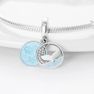 Macro detail of silver charm featuring blue moon and whale tail with sparkling zircons