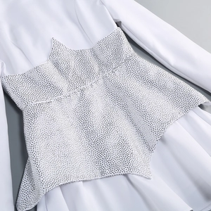 Dettaglio di strass scintillanti sulla vita di un elegante abito bianco a maniche