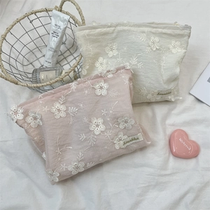 Close-up of floral embroidery on two premium toiletry bags in pink and cream beige