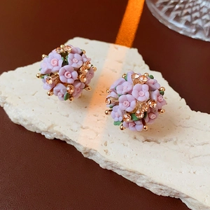 Makroaufnahme von 3D-Blumenohrringen mit lila Blütenblättern und funkelnden Strasssteinen