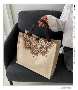 Detail of jute tote bag with brown mandala pattern and braided handles on a sofa