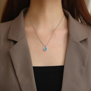 Détail d'un collier chaîne argentée avec pendentif ovale en pierre bleue sur un mannequin