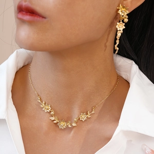 Détail d'un ensemble de bijoux fleurs dorées avec cristaux porté par un modèle