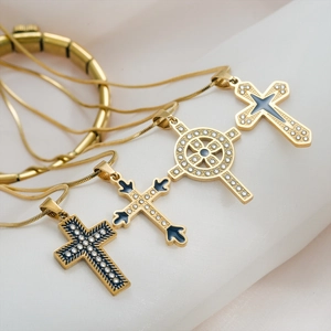 Détail de quatre colliers croix dorés avec zircons et émail sur soie blanche