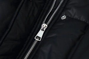 Close-up of black padded jacket with silver metal zipper and snap button detail