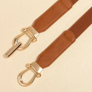 Detail of elegant brown elastic waist belt with a polished gold U-shaped metal buckle