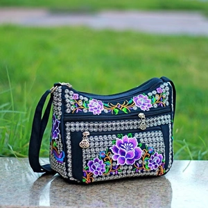 Detailed embroidery on a black canvas crossbody bag with multiple zipper compartments