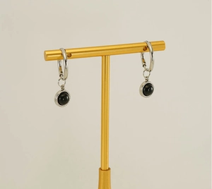 Detail of silver hoop earrings with black onyx pendants on a gold display stand