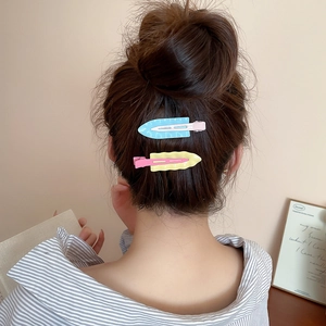Detail showing candy-colored wavy triangular hair clips worn on a bun hairstyle