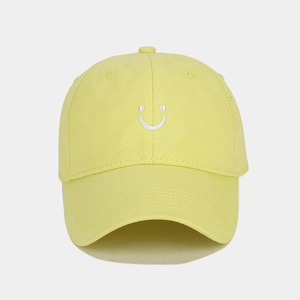 Close-up of yellow cotton baseball cap with white smiley face embroidery detail