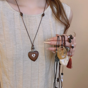 Detail of vintage heart pendant necklace with ethnic stone beads and red tassel accents