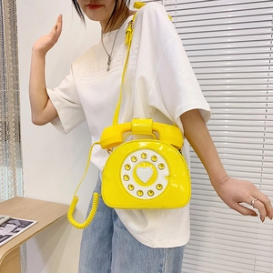 Macro shot of yellow patent leather phone bag with dial detail and heart motif