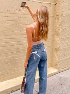 Women's high waist blue denim straight jeans featuring white bow detail on back pockets