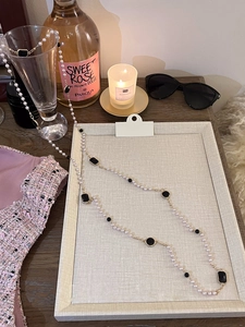 Elegant multi-layer pearl sweater necklace with black geometric charms and gold chain detail